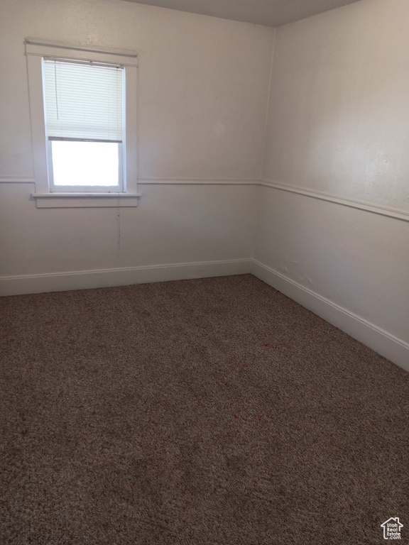 Carpeted spare room featuring baseboards