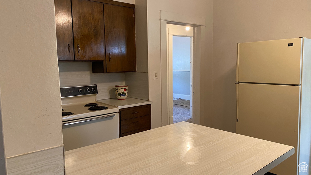 Kitchen with white appliances, dark brown cabinets, and light countertops