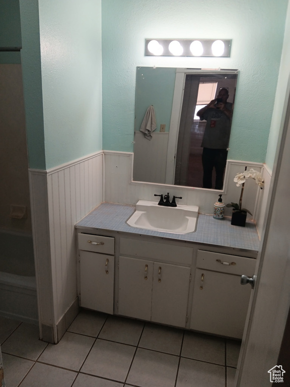 Bathroom featuring vanity, wainscoting, and tile patterned flooring