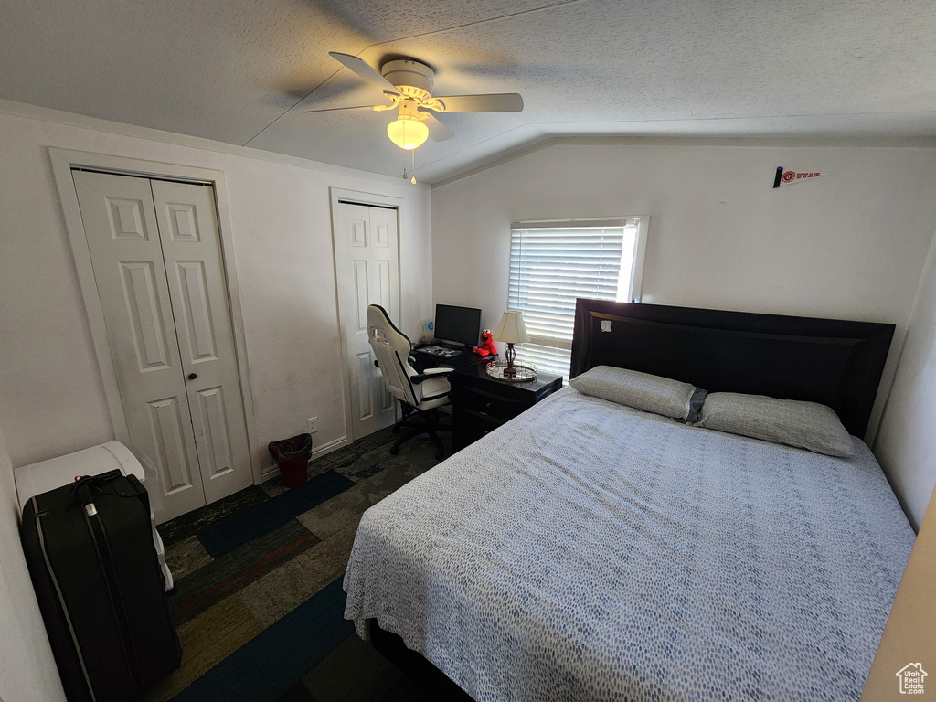 Bedroom featuring multiple closets, vaulted ceiling, ceiling fan, a desk, and baseboards
