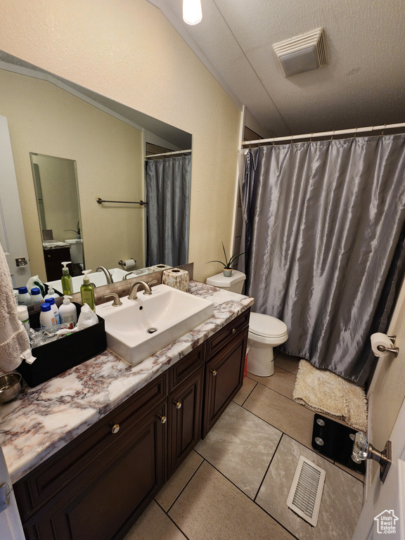 Bathroom featuring toilet, vanity, tile patterned flooring, and curtained shower