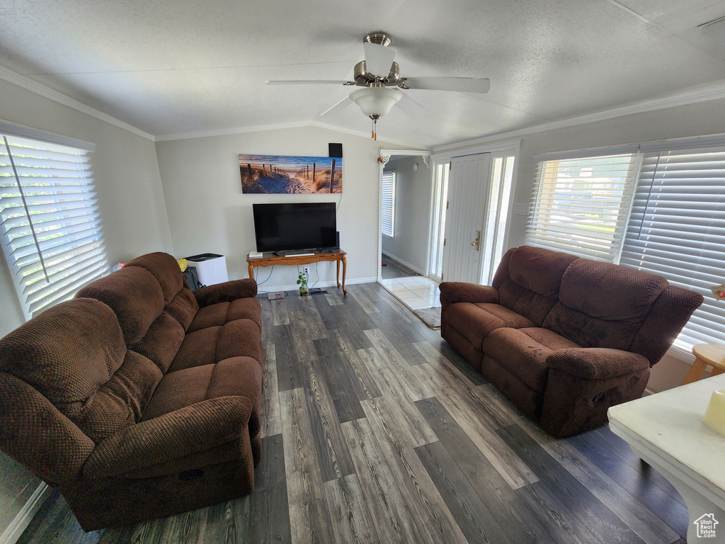 Living room featuring dark wood finished floors, ceiling fan, lofted ceiling, baseboards, and ornamental molding