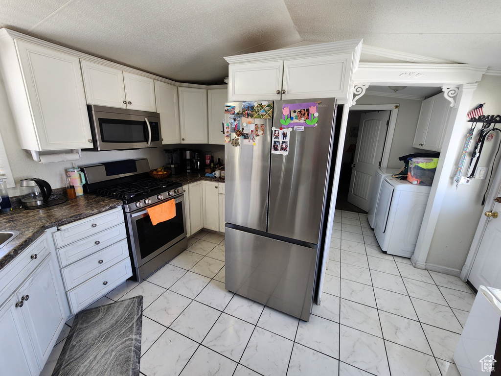 Kitchen featuring stainless steel appliances, light marble finish flooring, white cabinets, washer / clothes dryer, and vaulted ceiling