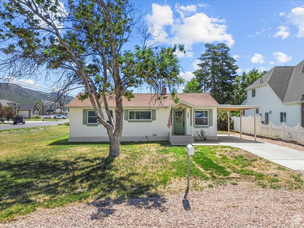 View of front of property featuring concrete driveway, stucco siding, and a carport