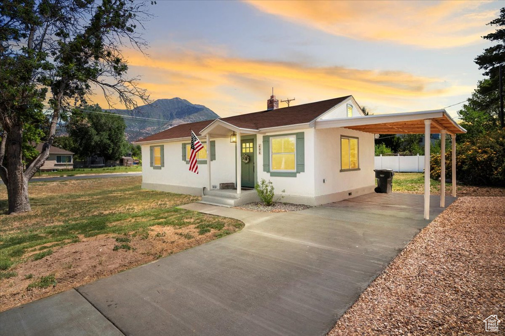 View of front facade with driveway, a carport, stucco siding, and a chimney