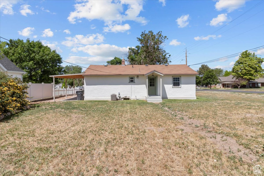 Rear view of property featuring stucco siding, entry steps, an attached carport, and cooling unit