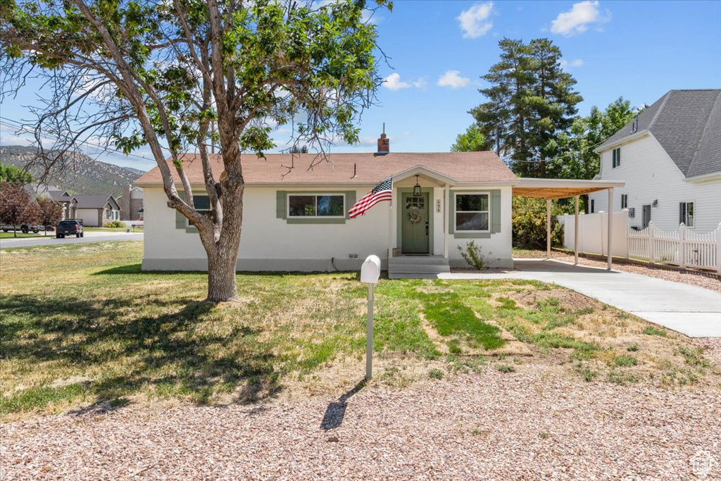 View of front of house with concrete driveway, a carport, and a mountain view
