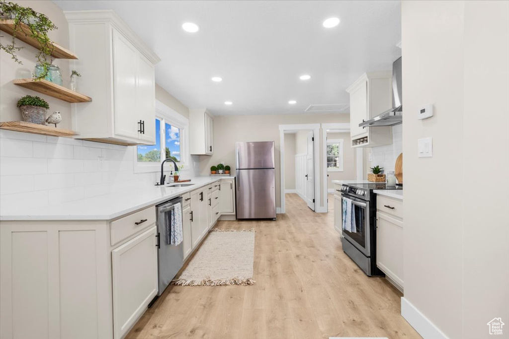 Kitchen with stainless steel appliances, wall chimney range hood, a sink, open shelves, and recessed lighting