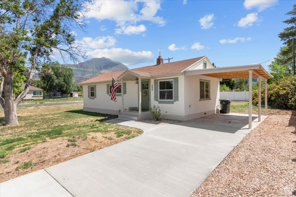 Single story home featuring concrete driveway, a carport, a mountain view, and stucco siding