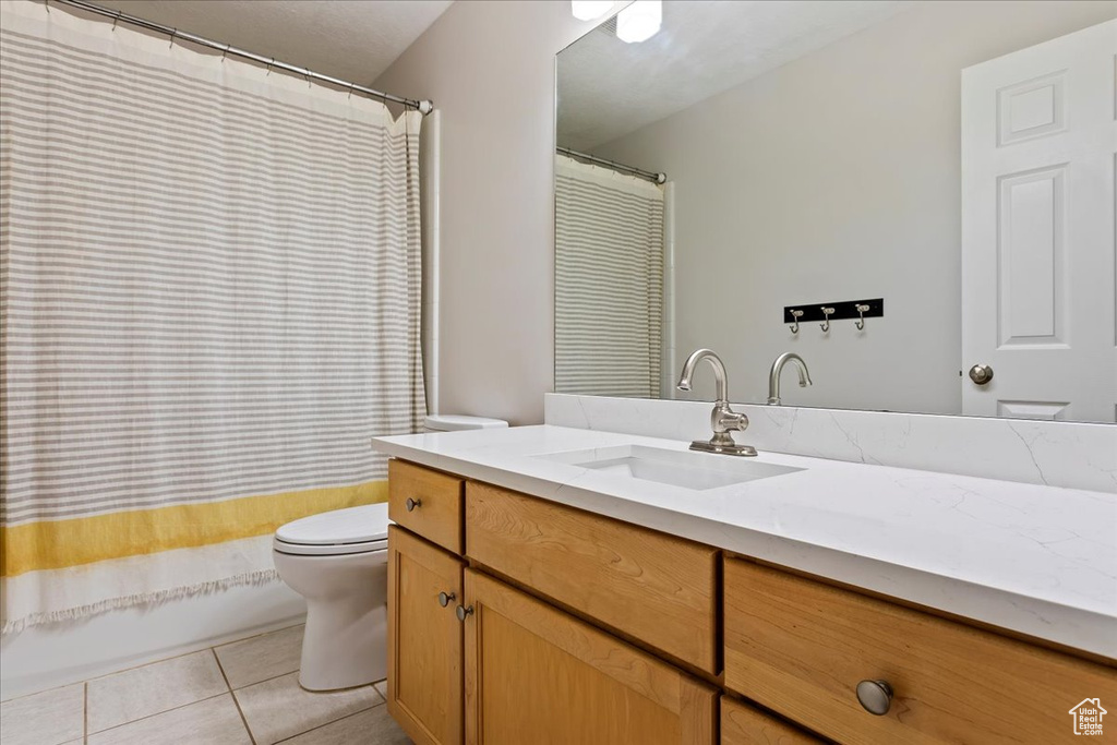Bathroom with toilet, vanity, tile patterned flooring, and shower / bath combo