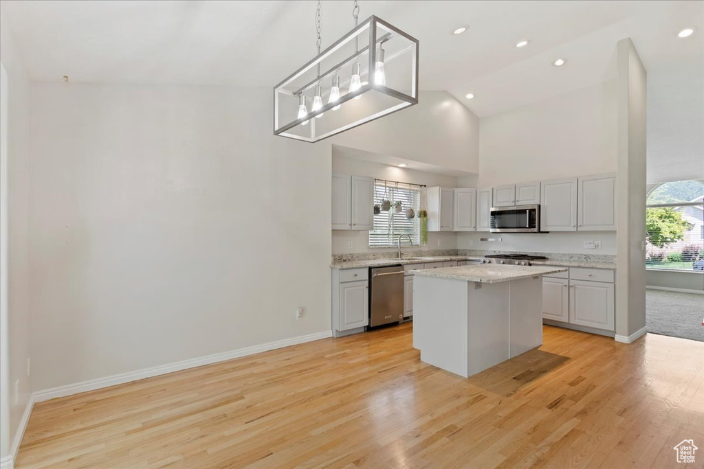 Kitchen featuring appliances with stainless steel finishes, high vaulted ceiling, baseboards, light wood-type flooring, and recessed lighting