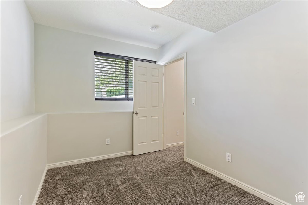 Carpeted spare room with baseboards and a textured ceiling