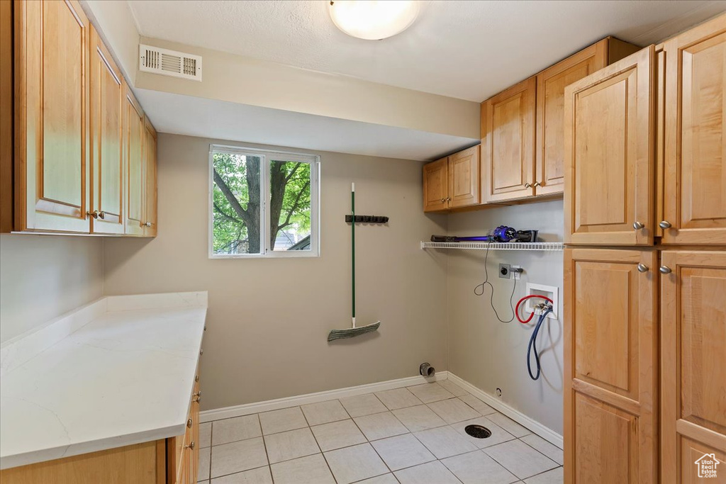 Laundry room featuring hookup for an electric dryer, cabinet space, washer hookup, light tile patterned flooring, and hookup for a gas dryer