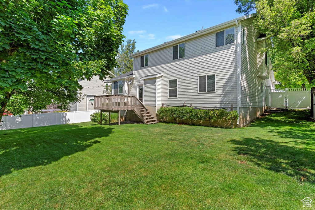 Rear view of property featuring stairway, a wooden deck, and a gate