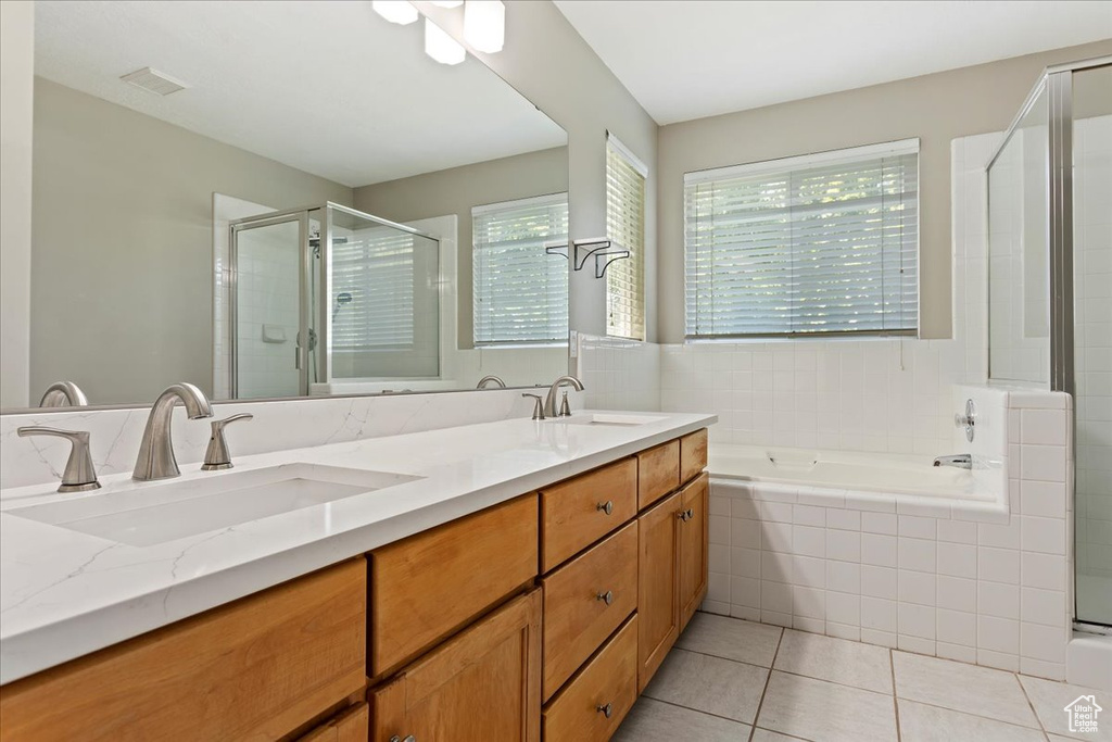 Full bathroom featuring plenty of natural light, double vanity, a shower stall, and a bath