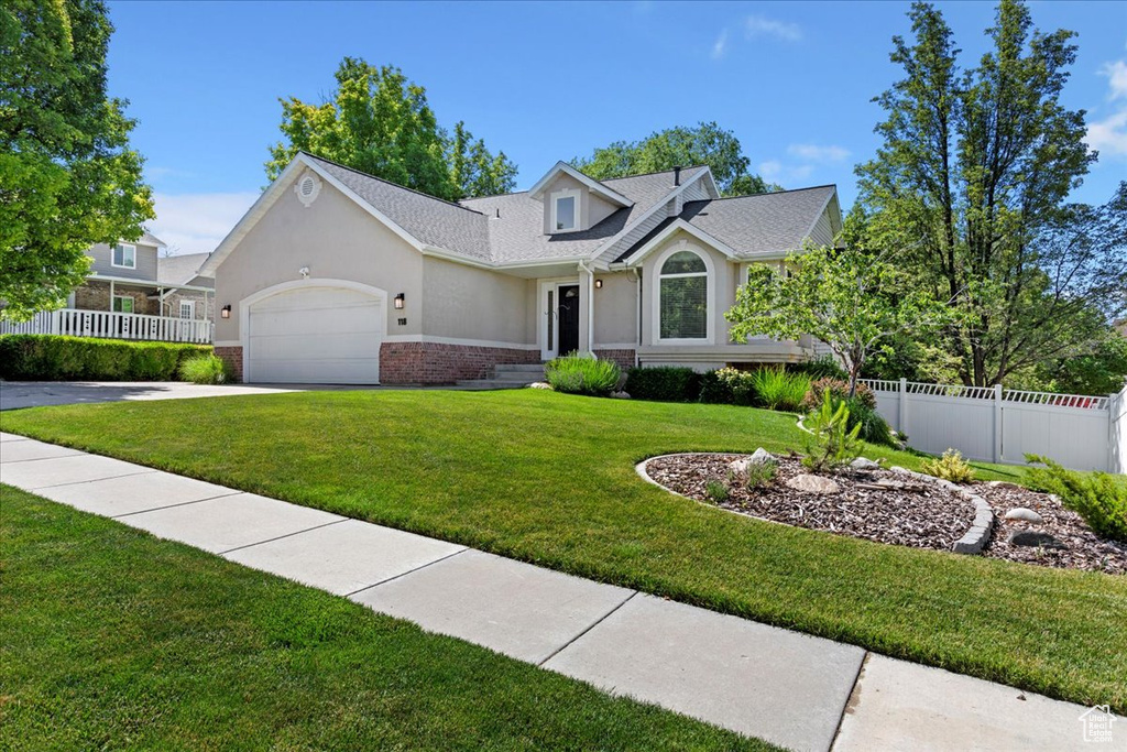 Traditional-style house with brick siding, stucco siding, a garage, driveway, and a shingled roof