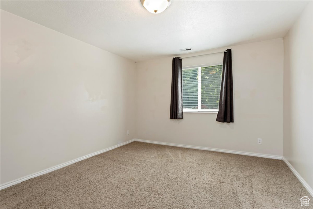 Carpeted spare room featuring baseboards