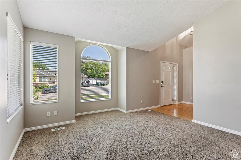 Carpeted spare room with baseboards and a textured ceiling