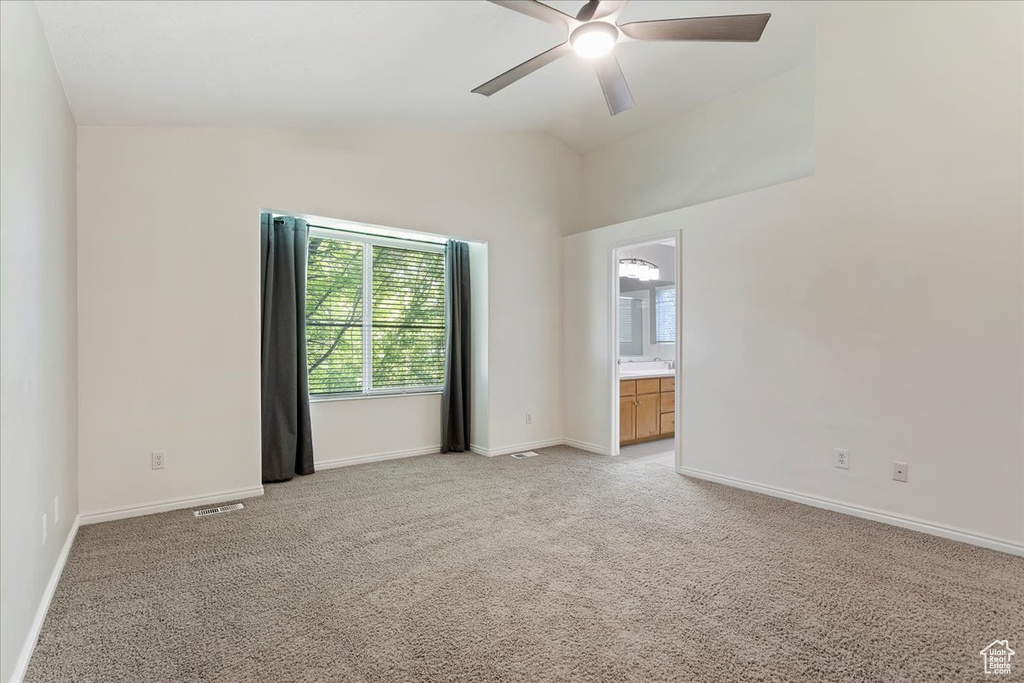 Unfurnished room featuring ceiling fan, light carpet, lofted ceiling, and baseboards
