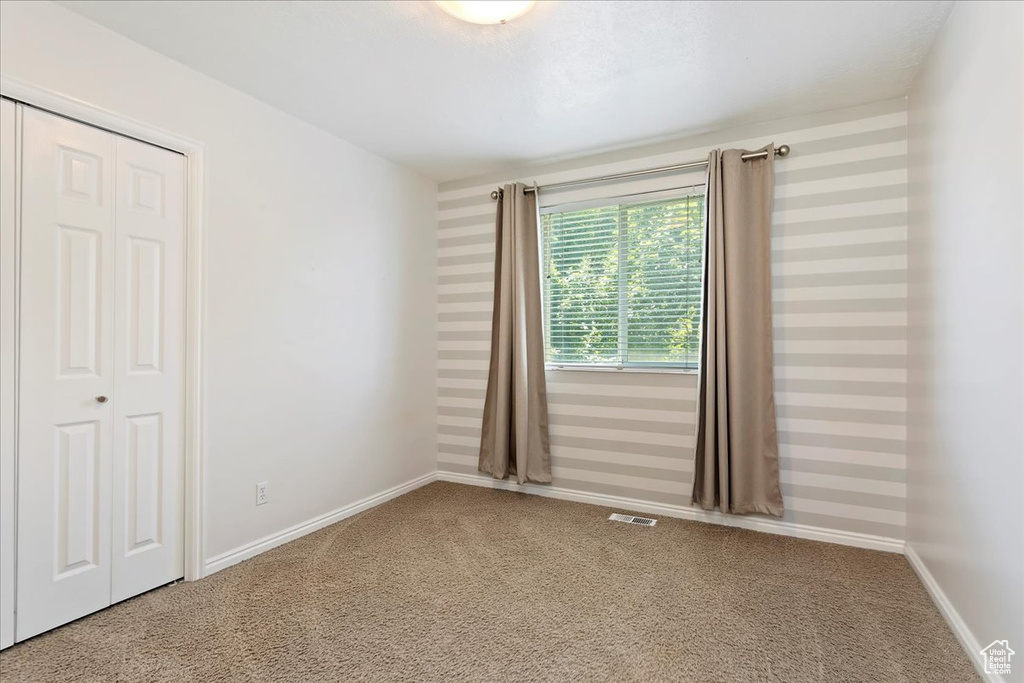 Carpeted spare room with wallpapered walls and baseboards