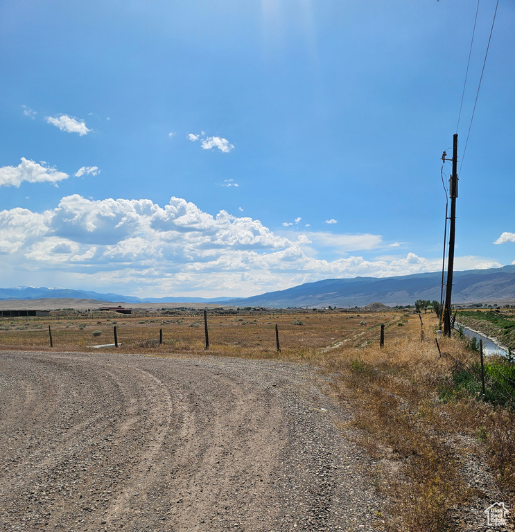 View of dirt / gravel road with a view of rural / pastoral area and a mountain view