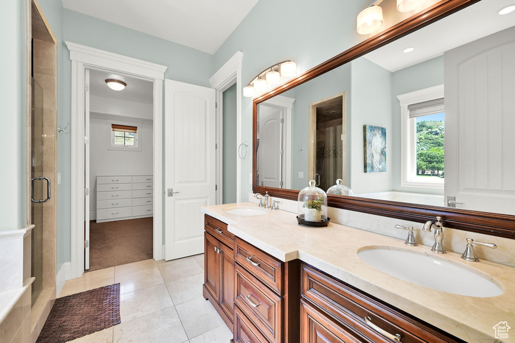 Full bath featuring an enclosed shower, healthy amount of natural light, double vanity, and tile patterned flooring