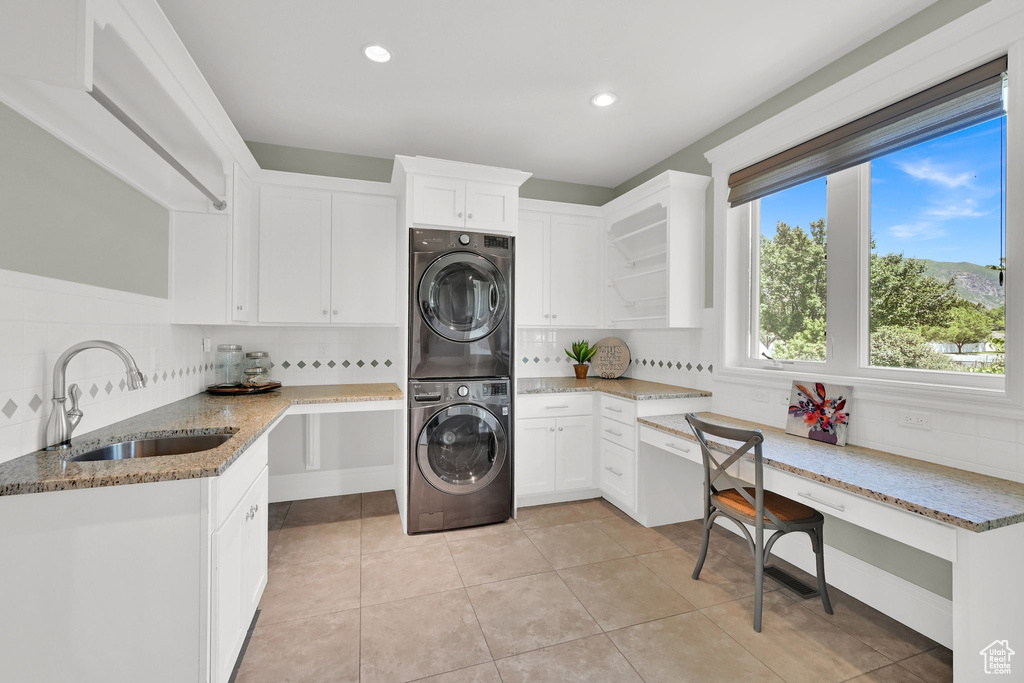 Laundry area with estacked washer and dryer, a sink, light tile patterned floors, and recessed lighting