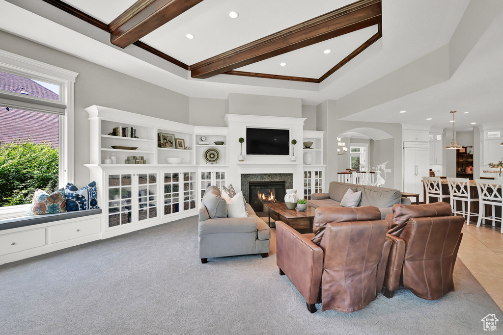 Living area with arched walkways, recessed lighting, a glass covered fireplace, light carpet, and beam ceiling