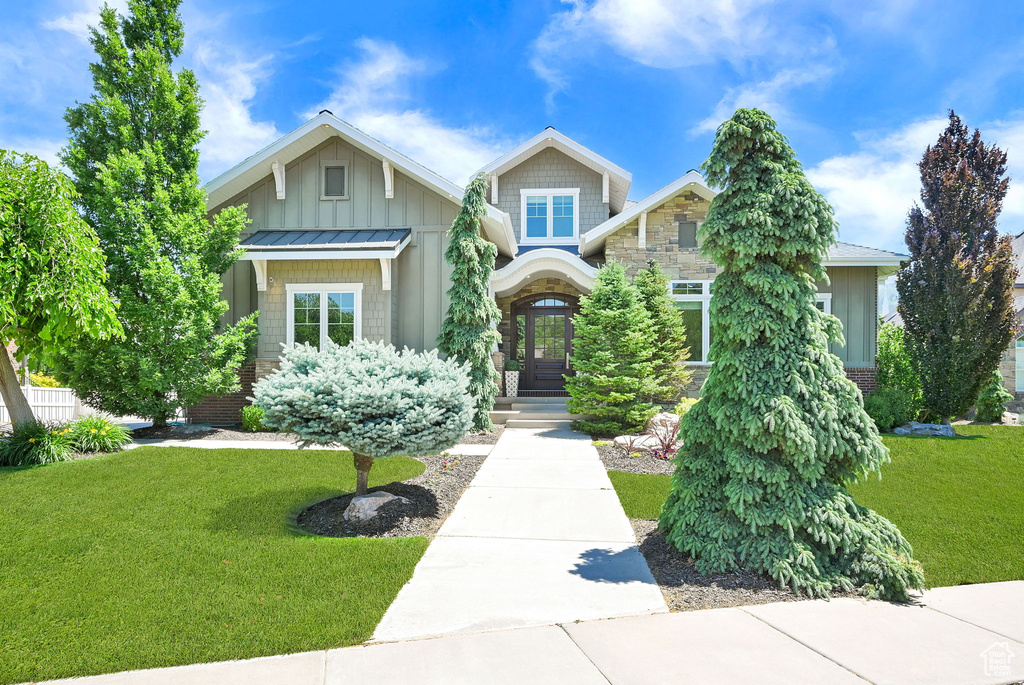 Craftsman house with a front lawn, a standing seam roof, board and batten siding, and metal roof