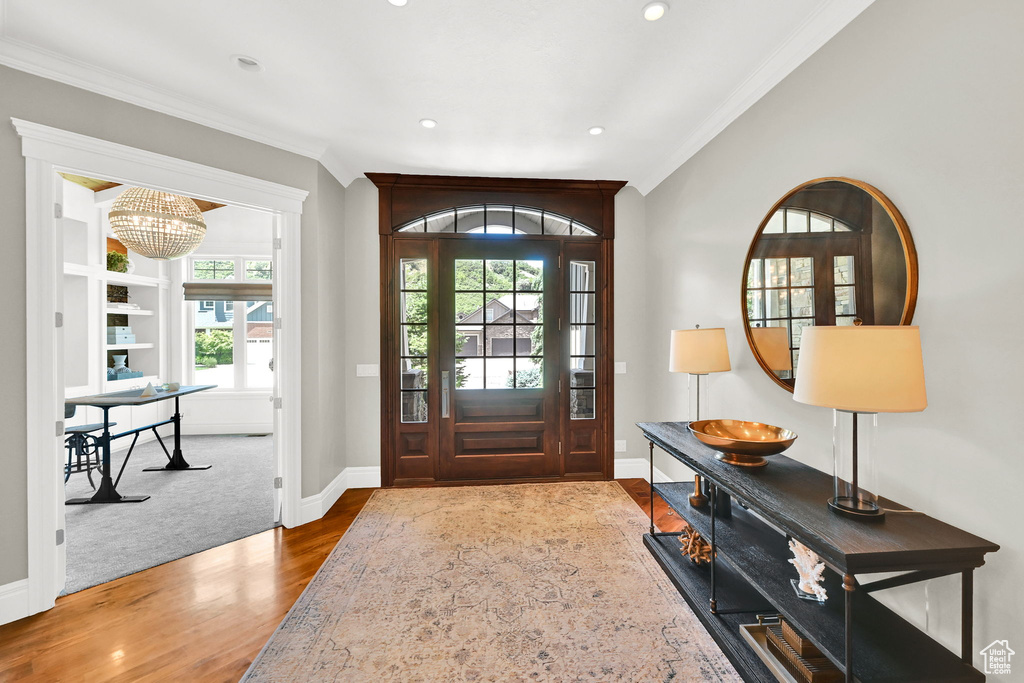 Entryway featuring crown molding, wood finished floors, baseboards, recessed lighting, and a chandelier