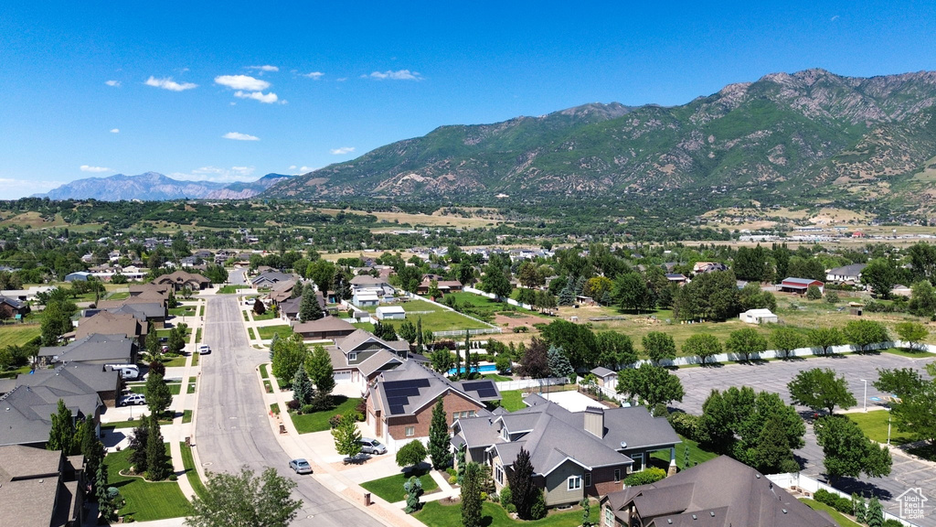 Aerial view of property and surrounding area featuring mountains and nearby suburban area