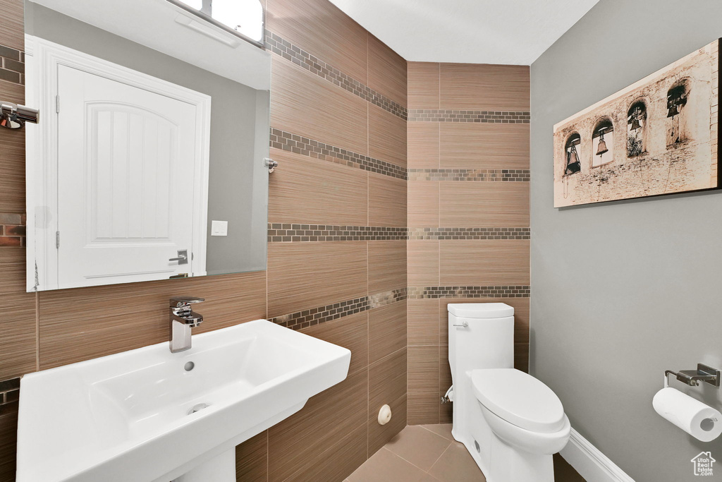 Bathroom featuring tile walls, a sink, toilet, and tile patterned floors