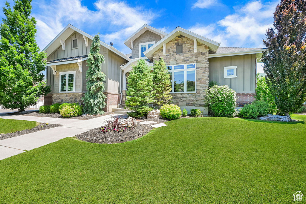 Craftsman-style house featuring board and batten siding, a front yard, and stone siding