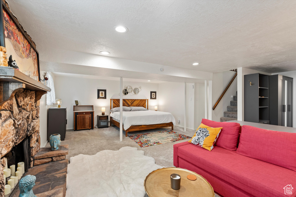 Carpeted bedroom with recessed lighting, a textured ceiling, baseboards, and a stone fireplace