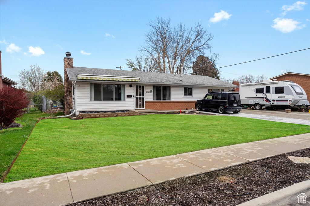 View of front of house featuring a chimney, a front yard, brick siding, and concrete driveway