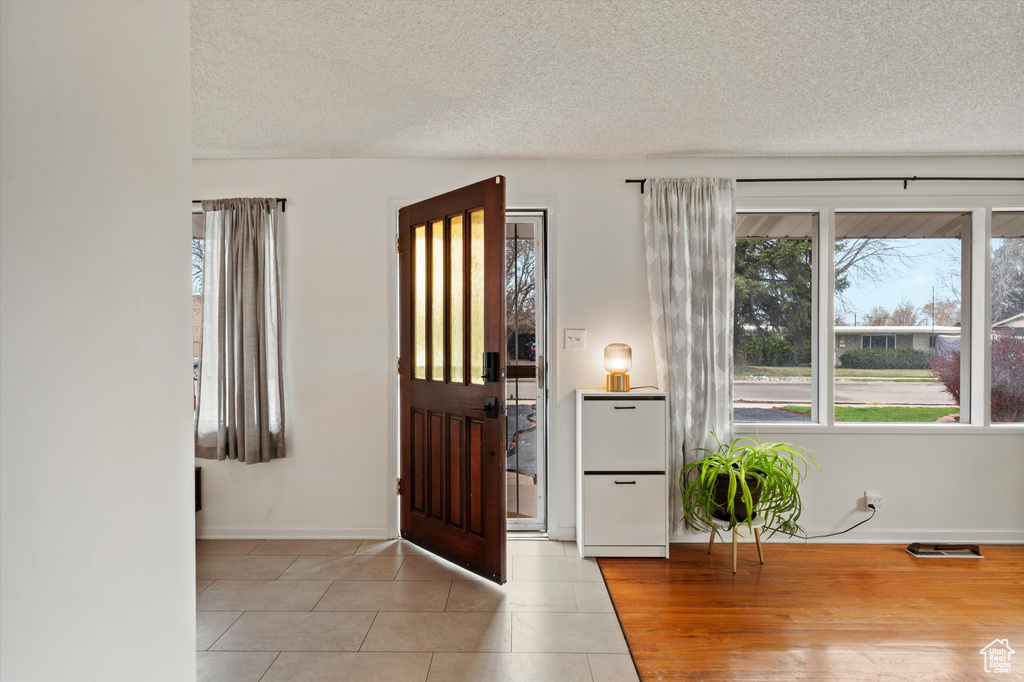 Entrance foyer with healthy amount of natural light, a textured ceiling, baseboards, and light tile patterned floors