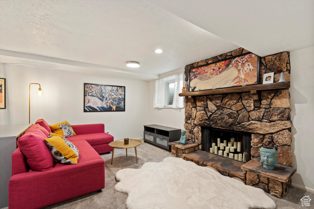 Living room with carpet floors, a stone fireplace, and baseboards