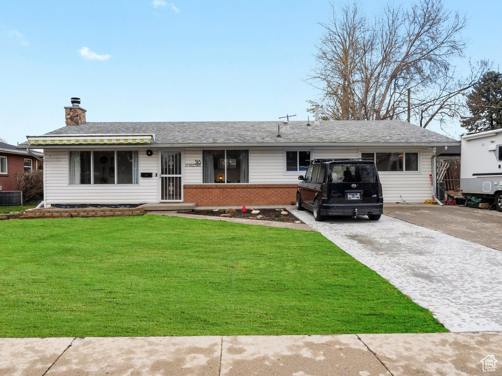 Single story home with driveway, a chimney, a front yard, brick siding, and central AC