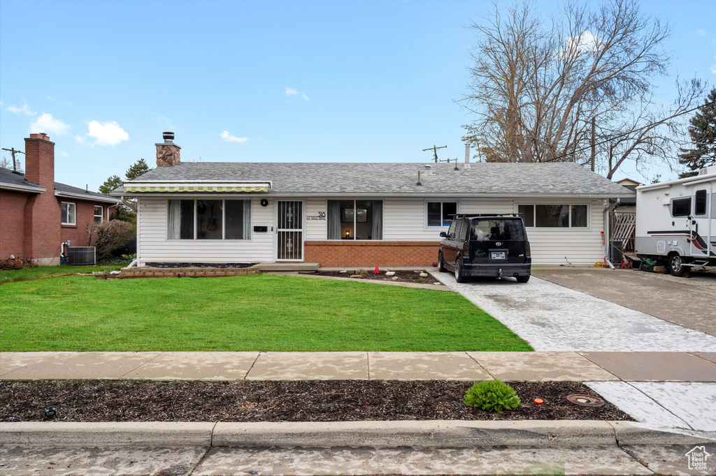 Ranch-style home featuring central AC, a front yard, driveway, a chimney, and brick siding