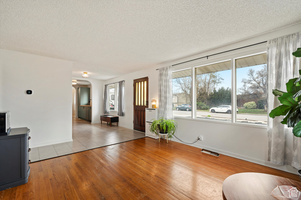 Living area featuring arched walkways, a textured ceiling, wood finished floors, and baseboards