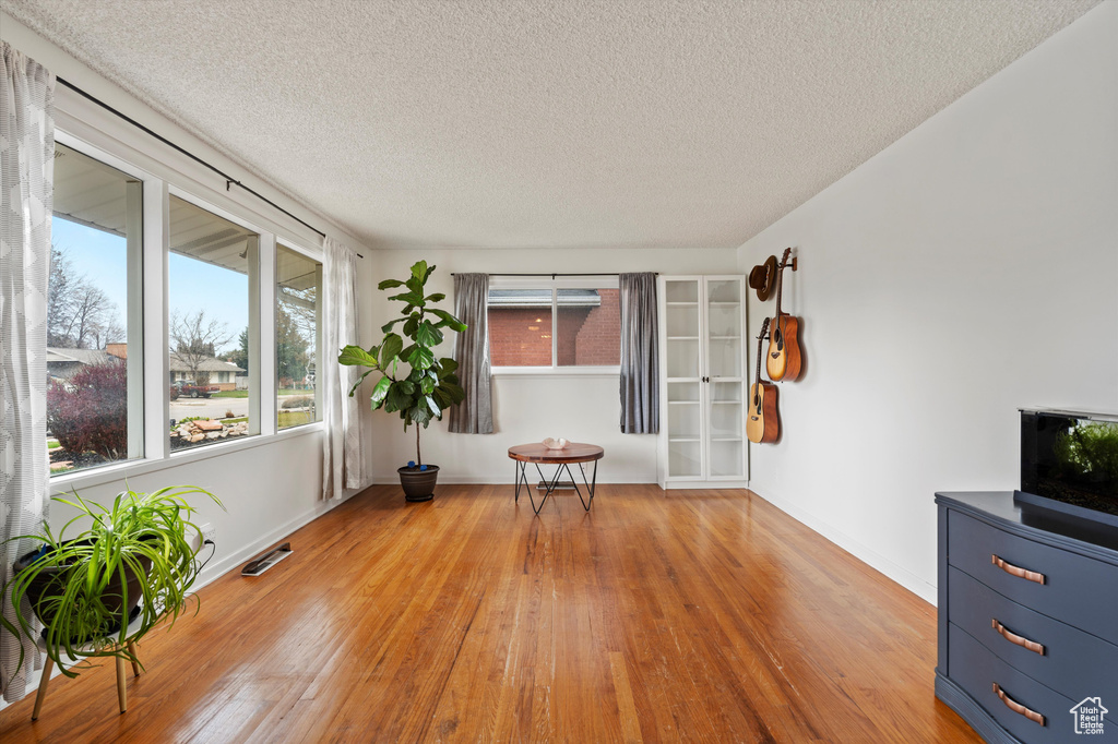 Spare room featuring light wood-type flooring, a textured ceiling, and baseboards