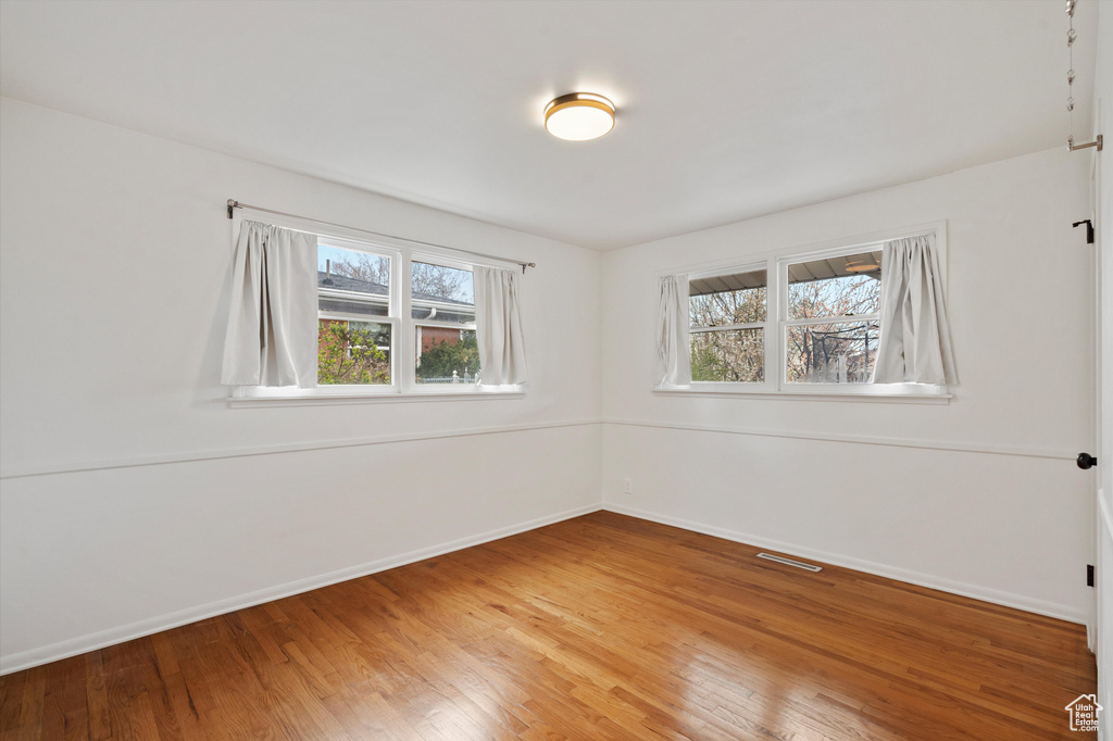 Unfurnished room with healthy amount of natural light, light wood-style floors, and baseboards