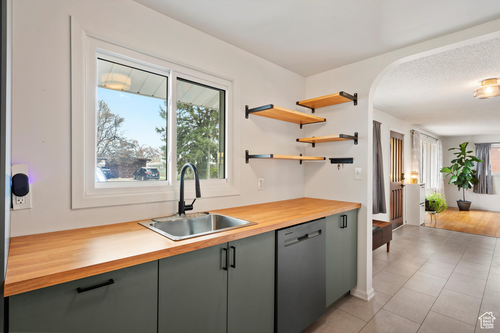 Kitchen featuring stainless steel dishwasher, a sink, butcher block counters, and plenty of natural light