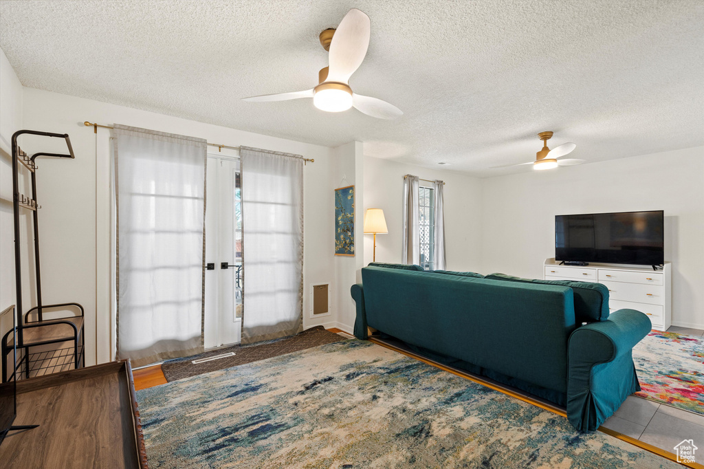 Living area featuring a ceiling fan and a textured ceiling