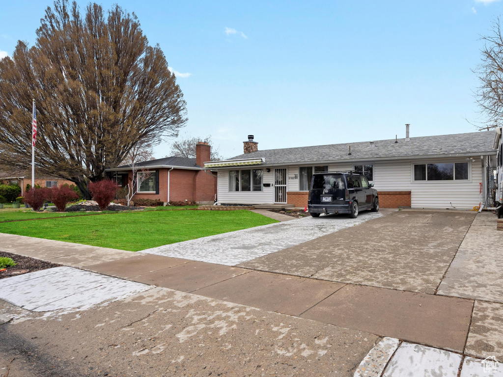 Single story home featuring brick siding, concrete driveway, and a front yard