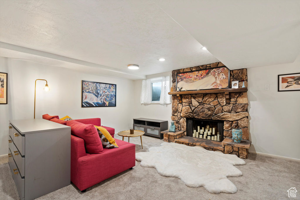 Living room with baseboards, carpet flooring, a stone fireplace, and recessed lighting