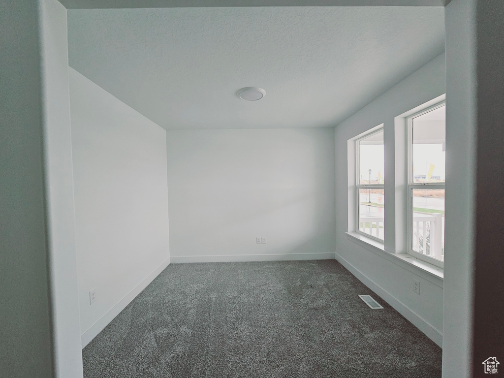 Unfurnished room with dark colored carpet and baseboards
