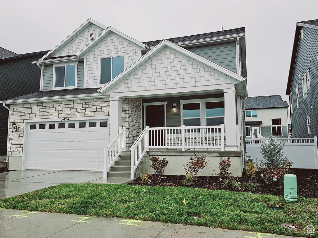 View of front of home with a porch, driveway, and an attached garage
