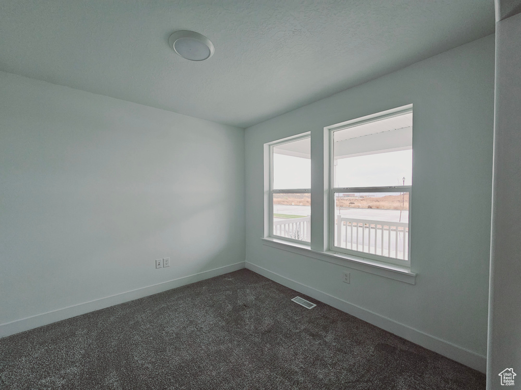 Spare room with baseboards and dark carpet