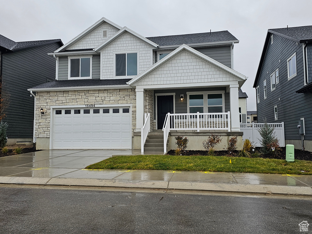 Craftsman inspired home featuring a porch, concrete driveway, an attached garage, and stone siding